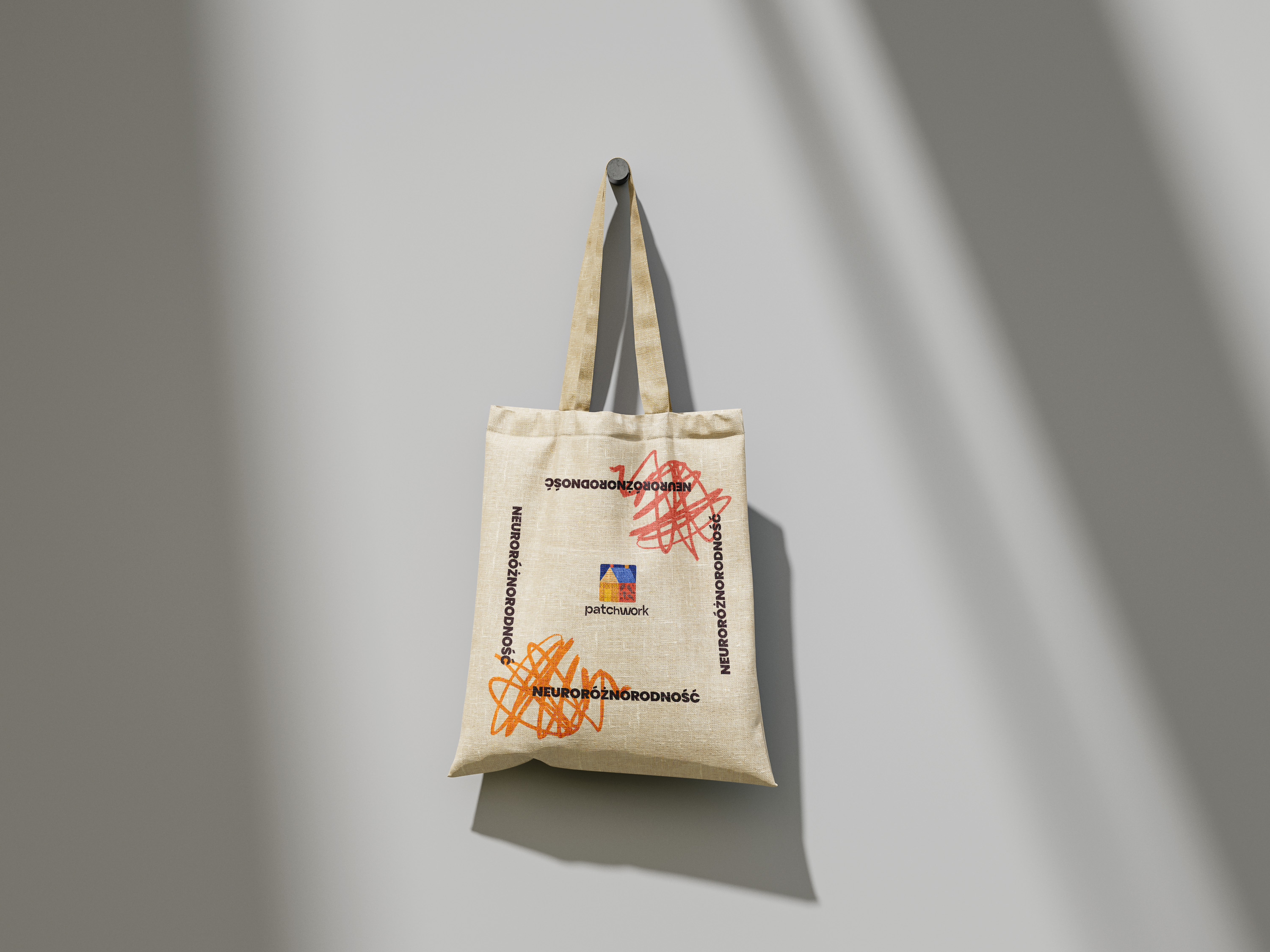 A tote bag with bold orange and red patterns showcased on a background of a wall