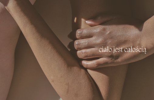 a close up photo of a hand resting on an arm, the company tagline "the body is a wholeness" overlays on the image