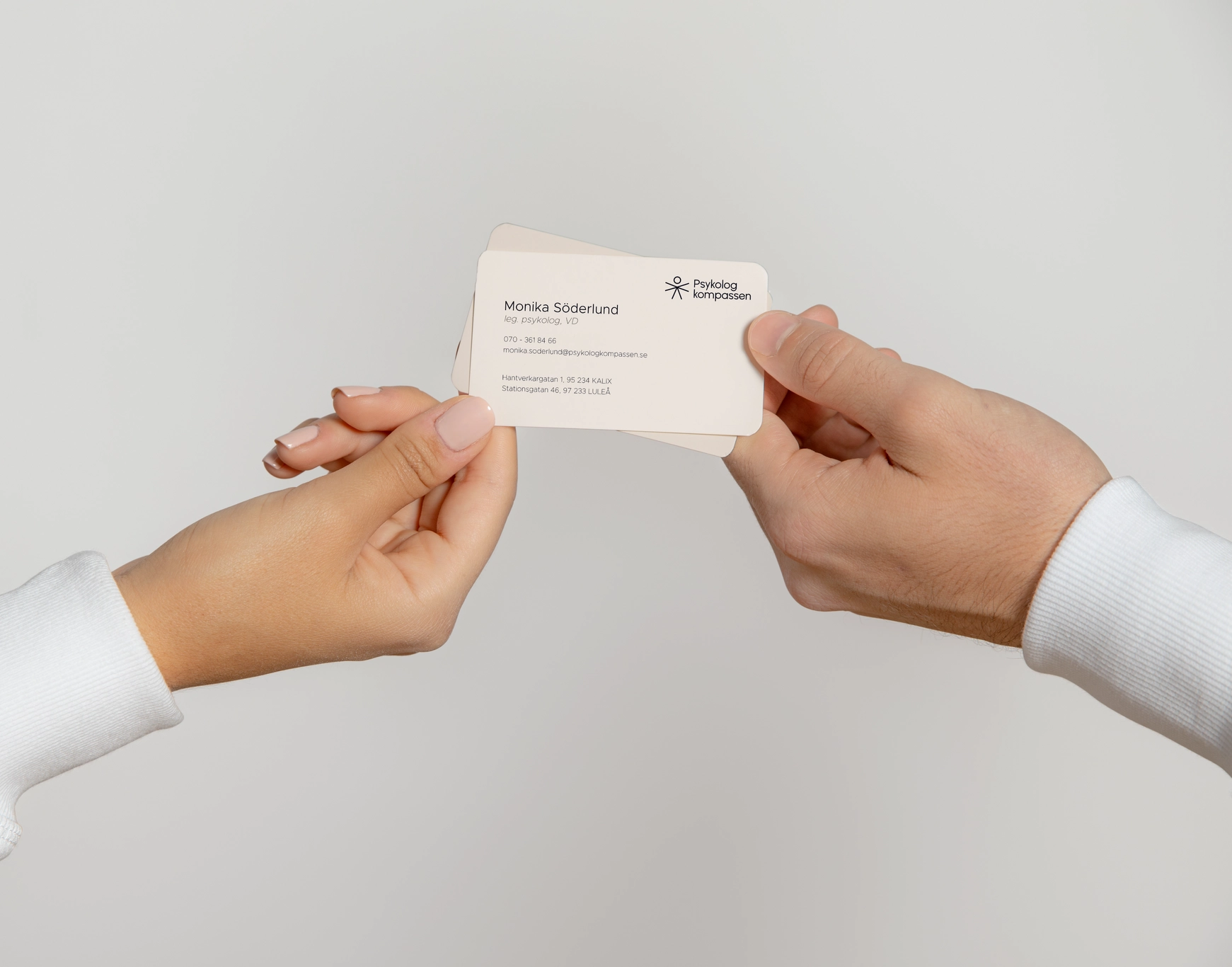 a close up of two hands passing each other business card with details of the owner of Psykologkompassen
