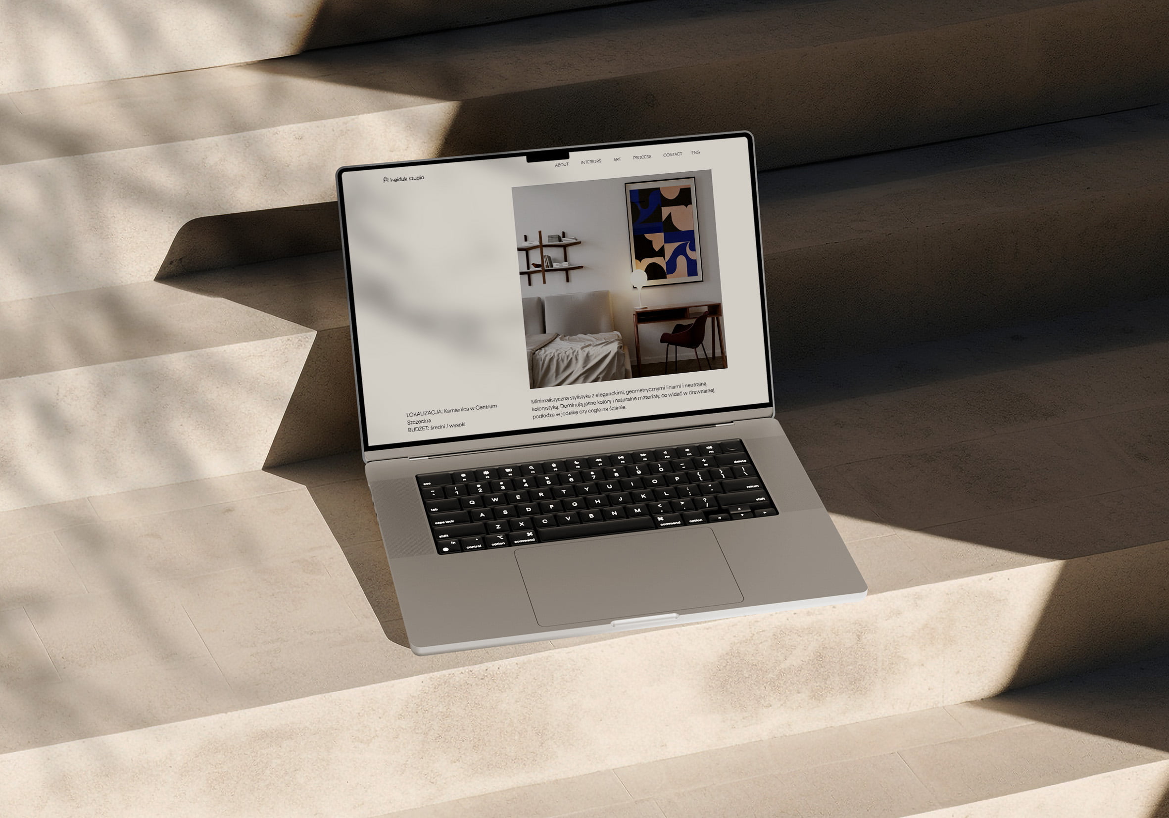 Open laptop standing on steps, displaying a interior design studio's website