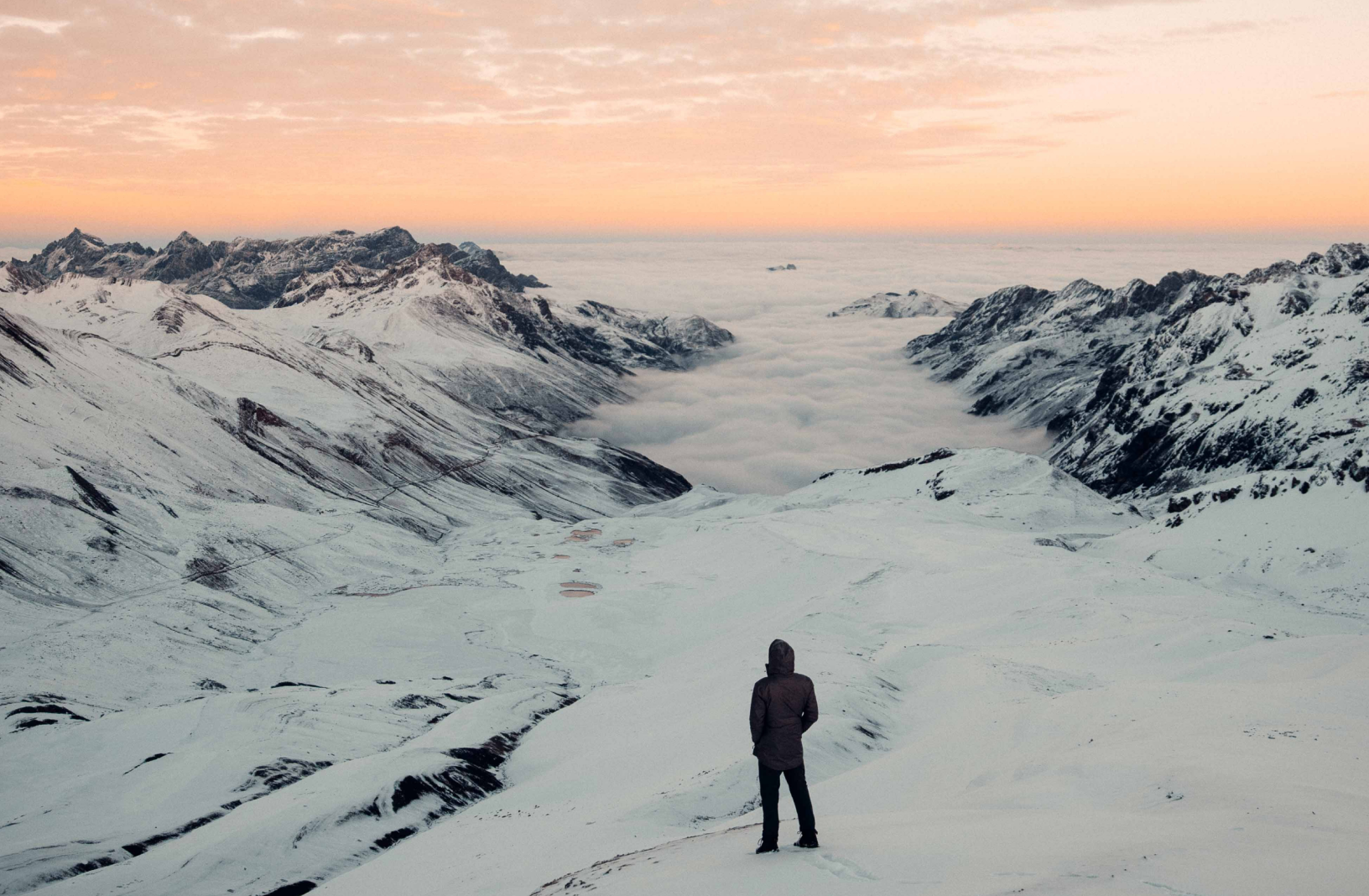 a man facing away from the camera looks at the landscape view in front of him