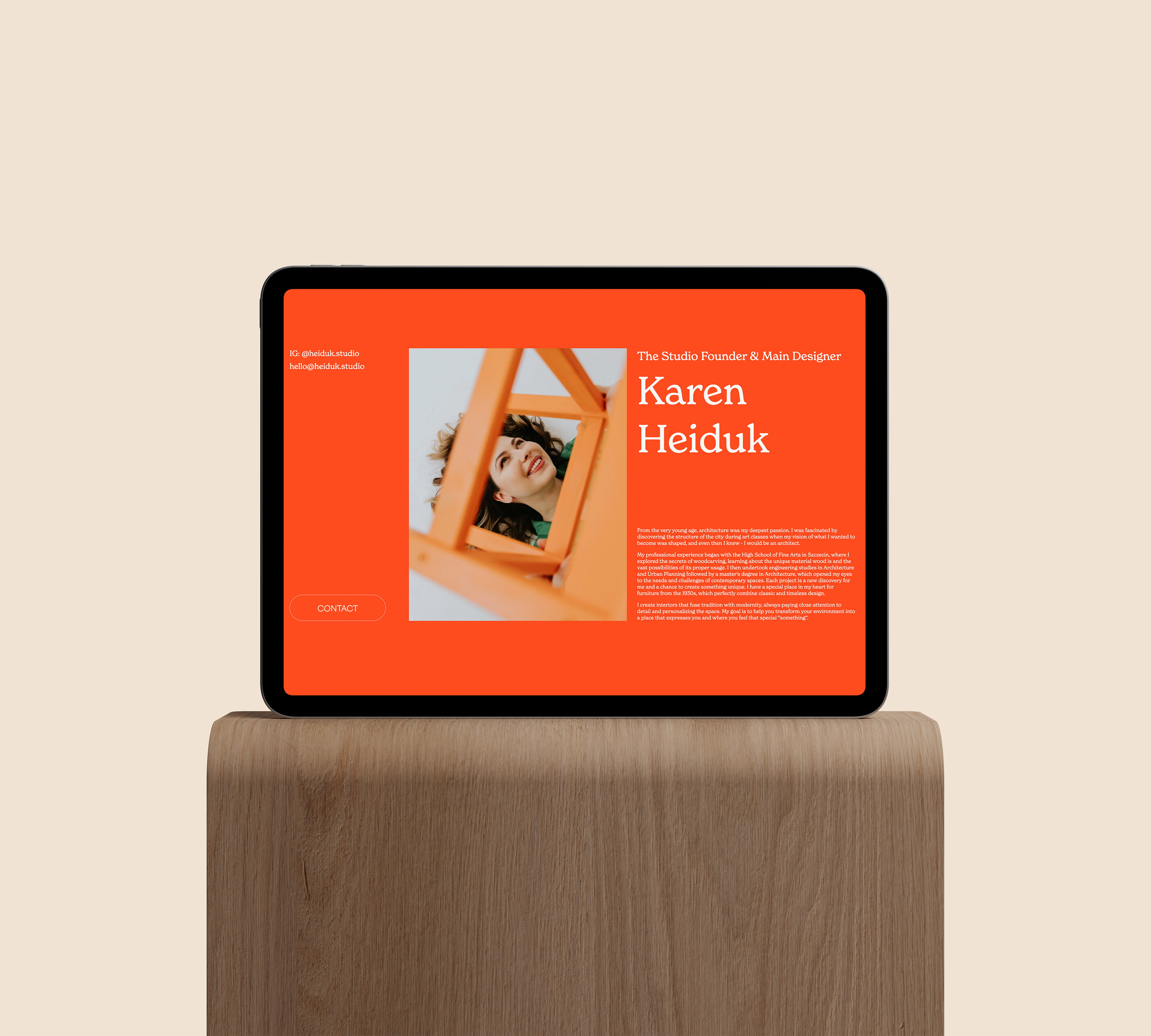 a tablet on a wooden stand, displaying a website with red background, white typography and a photo