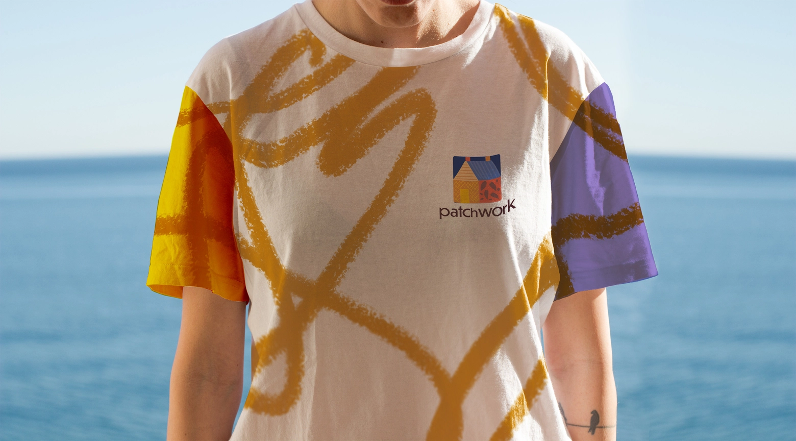A person wearing a vibrant t-shirt with a colorful line design and Patchwork organisation logo
